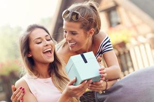 una foto de dos amigas haciendo un regalo sorpresa de cumpleaños