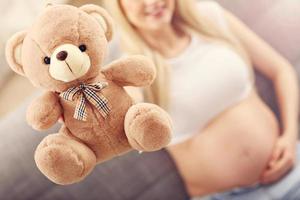 Happy pregnant woman with teddy bear photo