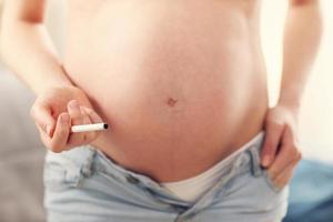 Close up of pregnant woman smoking cigarette at home photo