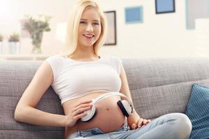 Young pregnant woman listening to music and sitting on sofa photo