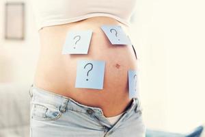 Photo of pregnant woman with question marks on belly