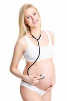 Pregnant woman holding stethoscope on belly photo