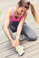 Female athlete runner touching foot in pain outdoors photo