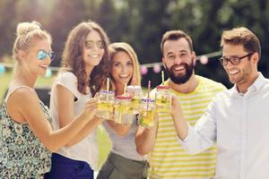 grupo de jóvenes animando y divirtiéndose al aire libre con bebidas foto