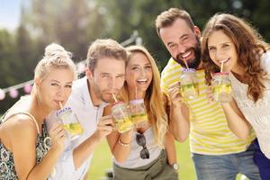 Group of young people cheering and having fun outdoors with drinks photo