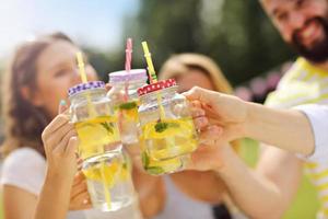 Group of young people cheering and having fun outdoors with drinks photo