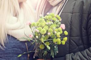 imagen que muestra a una pareja joven con flores saliendo en la ciudad foto