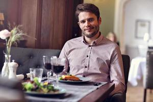 Handsome man waiting at table in restaurant photo