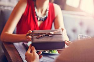 Midsection of romantic couple dating in restaurant and having present photo