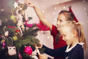 niños decorando arbol de navidad foto