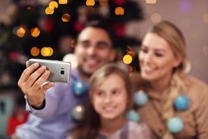 Happy family having fun during Christmas time and taking selfie photo