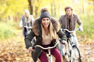 grupo de amigos en bicicleta en el bosque durante el otoño foto