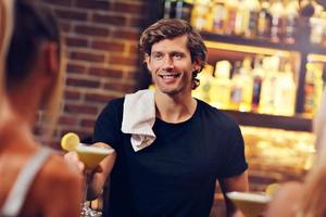 Handsome bartender serving cocktails in a pub photo