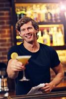 guapo camarero sirviendo cócteles en un pub foto