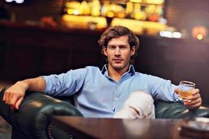 Young man sitting alone in bar with a glass of whisky photo