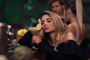 Young woman sitting alone in bar with a coctail photo