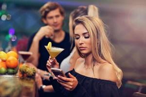 Young woman sitting alone in bar with a coctail photo