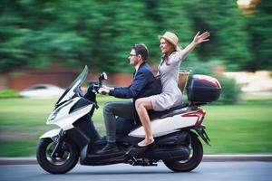 feliz pareja madura montando una moto en la ciudad en un día soleado foto