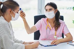 Doctor in mask explaining diagnosis to her female patient photo