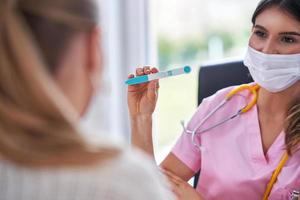 Doctor in mask explaining diagnosis to her female patient photo