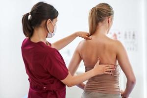 Physiotherapist in mask helping female patient photo