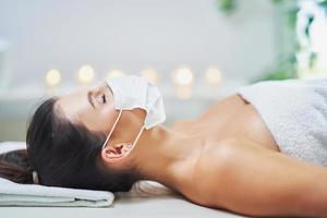 Adult woman in mask during relaxing massage in spa photo