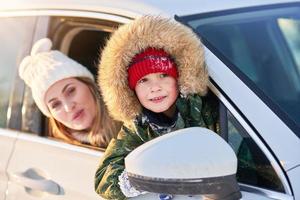 niño feliz con la madre en el coche durante el invierno foto