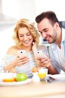 pareja feliz desayunando y usando un teléfono inteligente foto