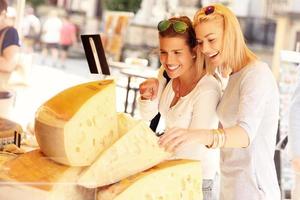 Two women shopping for cheese on food market photo