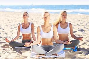 grupo de mujeres practicando yoga en la playa foto