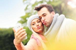 joven pareja romántica con smartphone en el parque en otoño foto