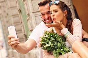 joven pareja romántica tomando selfie en la ciudad foto