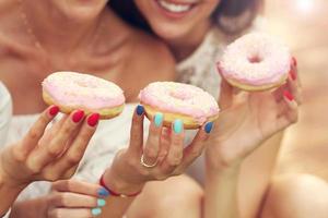 feliz grupo de amigos comiendo donuts al aire libre foto