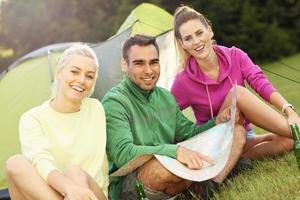 Group of friends camping in forest and looking at map photo