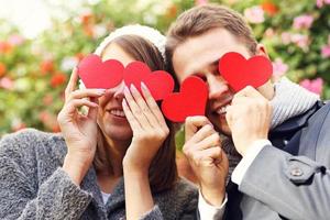 Happy couple covering eyes with hearts photo