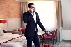 Young businessman in hotel room with smartphone photo