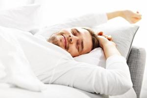 Handsome man stretching in bed photo