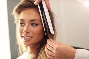 Hairdresser using hair straightener photo