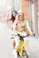 Two happy girl friends riding tandem bicycle photo