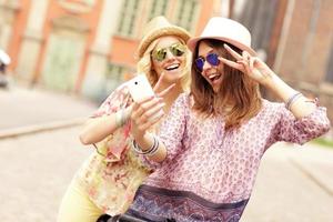 Two girl friends using smartphone while riding tandem bicycle photo