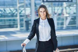 Elegant woman walking with bag and suitcase in the railway station photo