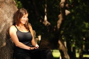 Young woman working on a laptop in the park photo
