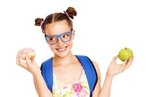 Schoolgirl with healthy and unhealthy lunch choices photo