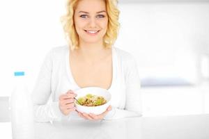 mujer joven comiendo cereal en la cocina foto