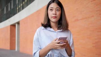 une jeune femme utilise un téléphone portable pour tenir le sol et jouer dehors par beau temps. video