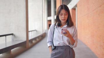 una niña que lee un mensaje en un teléfono inteligente da un paseo durante un recorrido a pie al aire libre. video