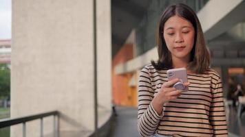 A woman wearing neat clothes uses a mobile phone to send messages and chat online. video