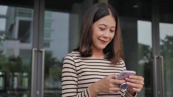 meisje cheques smartphone nieuws voeden terug van Universiteit vervelend straatkleding. buiten de deur video