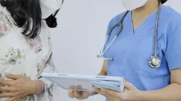 Auf einem Tablet wird ein Nahaufnahmevideo einer asiatischen Ärztin gezeigt, die mit einer Patientin spricht. video