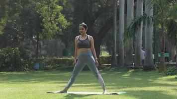 Video of a young woman standing in Utthita Trikonasana pose.